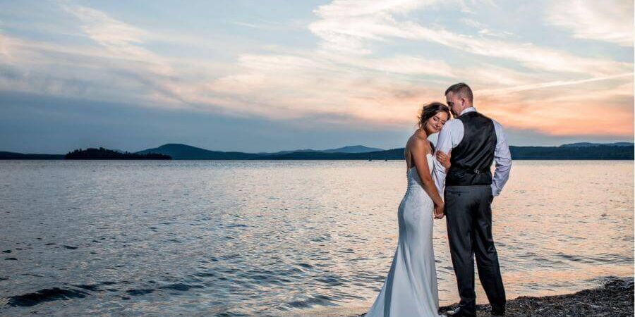 Loon Lodge Weddings wedding couple standing on the shore of Rangeley Lake at sunset